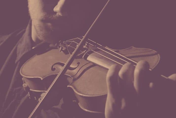 Soft dark image of a violinist head and shoulder playing the violin.